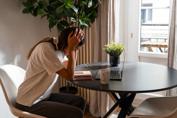 Exhausted,Young,Woman,Sitting,At,Home,With,Laptop,Holding,Her Santé mentale jeunes